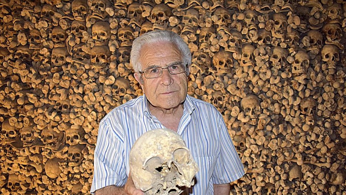 El sacerdote José Luis Velasco, con una calavera del osario de la iglesia de Wamba, pequeña población vallisoletana situada en los Montes Torozos.-AGRICOMUNICACIÓN