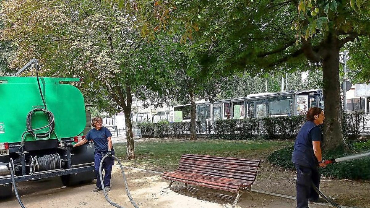 Dos trabajadoras municipales riegan los jardines del Poniente con el agua de un camión cistena.-E. M.