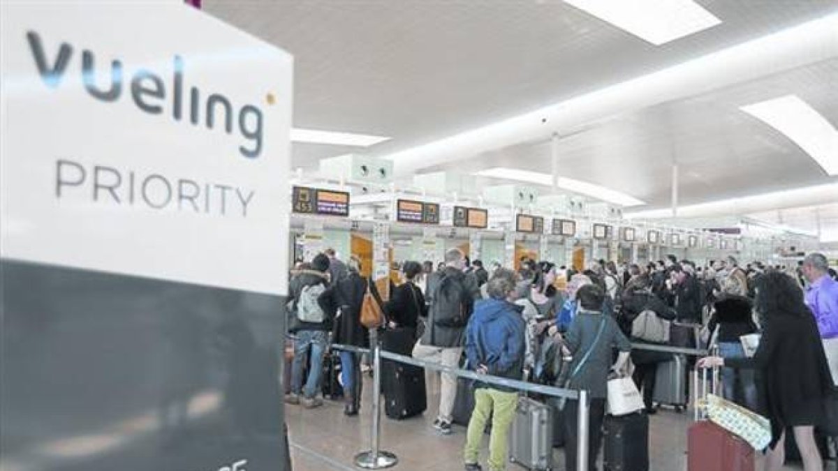 Colas de pasajeros en los mostradores de facturación de Vueling en El Prat .-Foto: DANNY CAMINAL