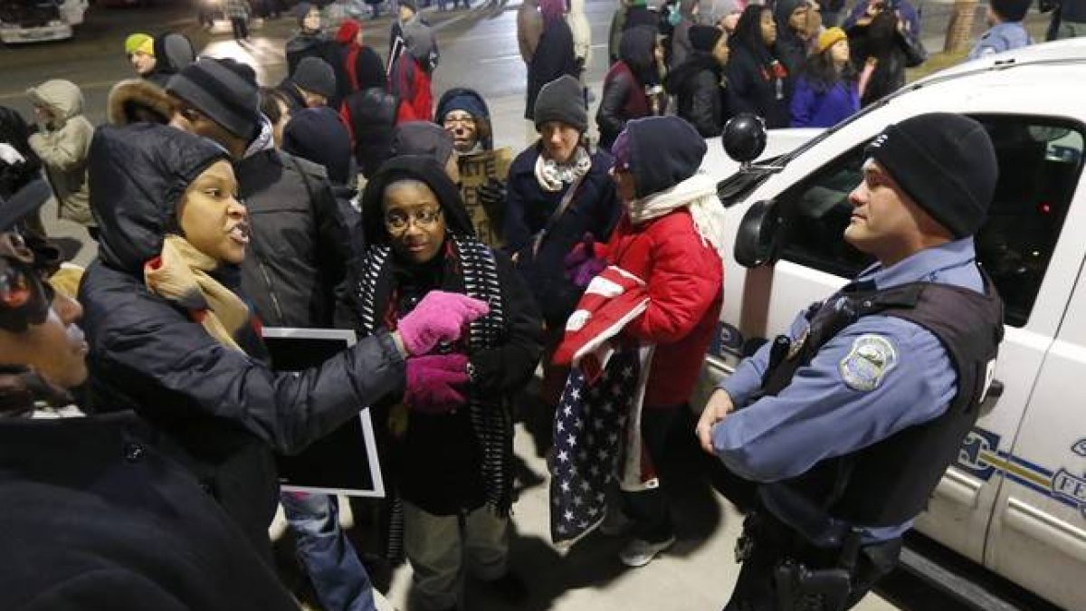 Una manifestante se encara con un policía, ante la comisaría de Ferguson, anoche, tras conocerse la decisión del Departamento de Justicia.-Foto:   AP / CHARLES REX ARBOGAST