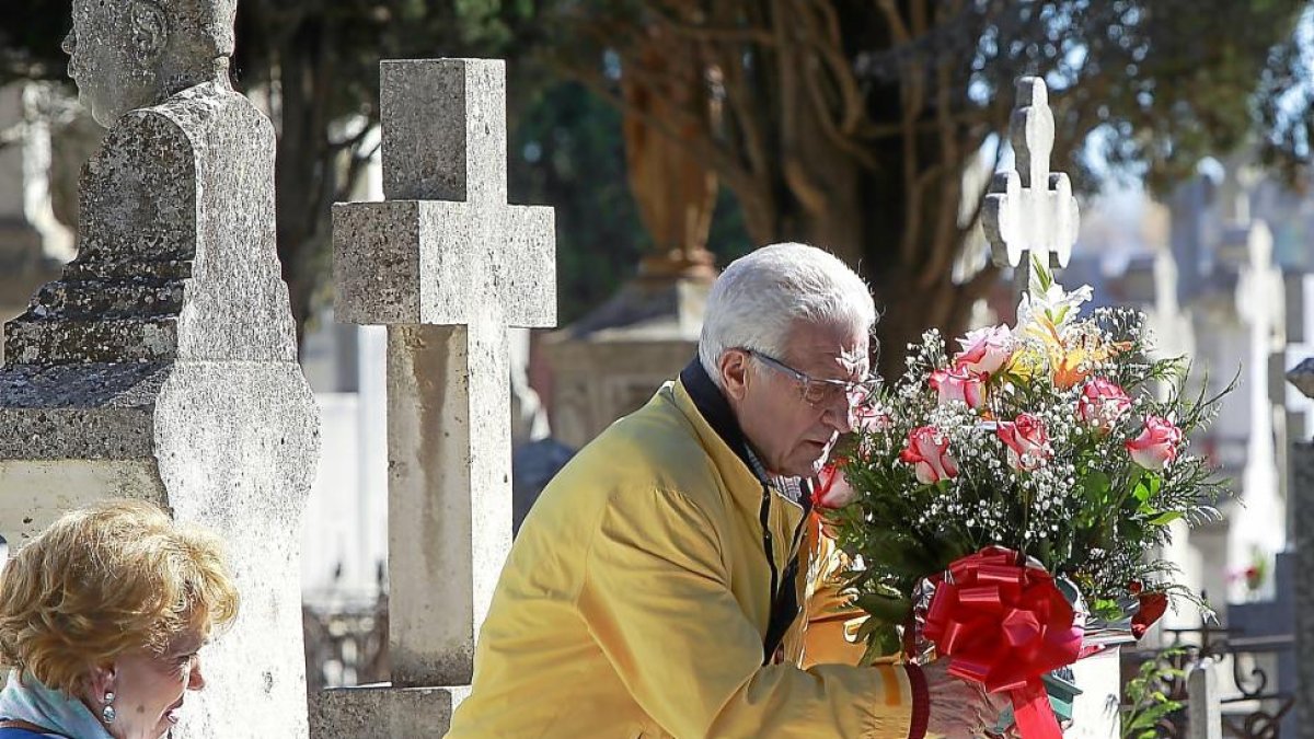 Un hombre deposita un centro de flores sobre una de las lápidas en la víspera del Día de Todos los Santos.-J.M.LOSTAU