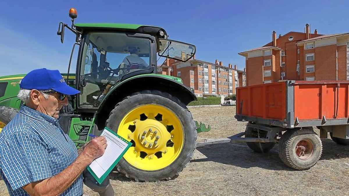 Imagen de un hombre junto a un tractor.-J.M.LOSTAU