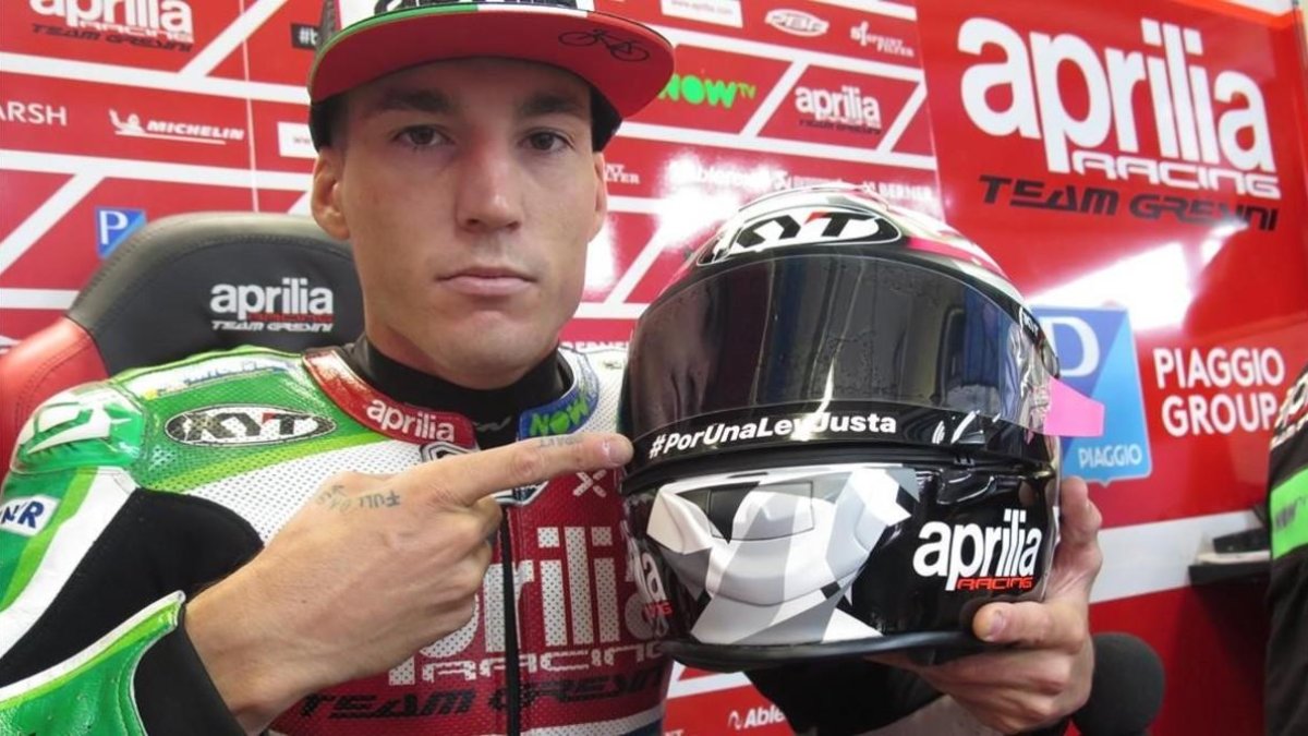Aleix Espargaró muestra, hoy, en Austria, la inscripción que luce en su casco. /-EMILIO PÉREZ DE ROZAS