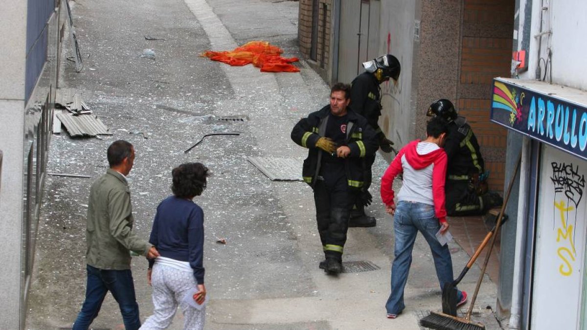 Varios vecinos del inmueble afectado por una explosión de butano en la calle San Lázaro en el centro de Ponferrada (León), regresan a sus casas después de las tareas de limpieza realizadas por los bomberos-Ical
