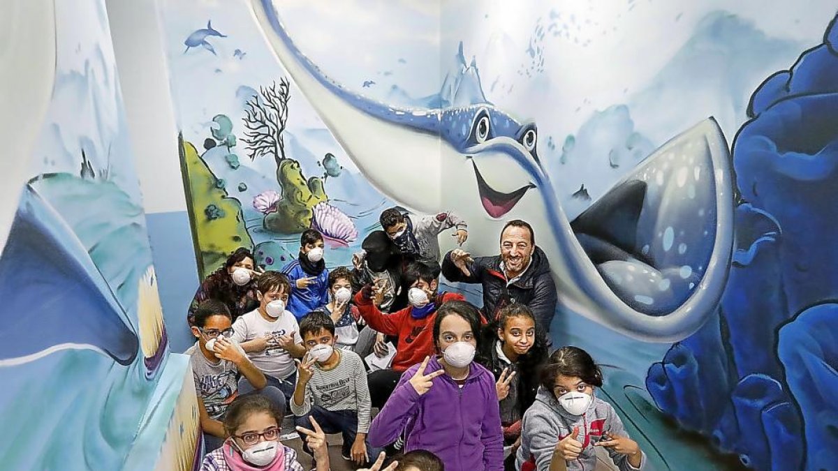 El director del colegio, Alberto Rodríguez, posa junto a los alumnos en el pasillo decorado con dibujos relacionados con el mar.-REPORTAJE GRÁFICO:J.M. LOSTAU