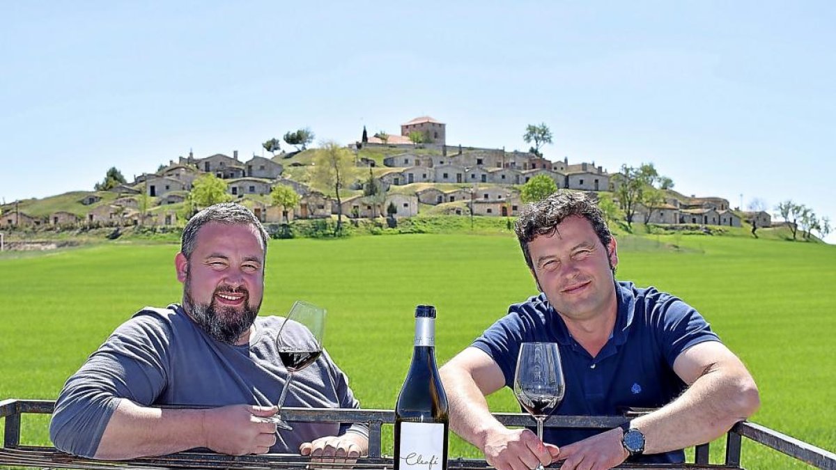 Los hermanos Quico y José Mari, con el tinto Cleofé dedicado a su abuela, ante el espectacular conjunto de bodegas subterráneas de Moradillo de Roa-ARGICOMUNICACIÓN