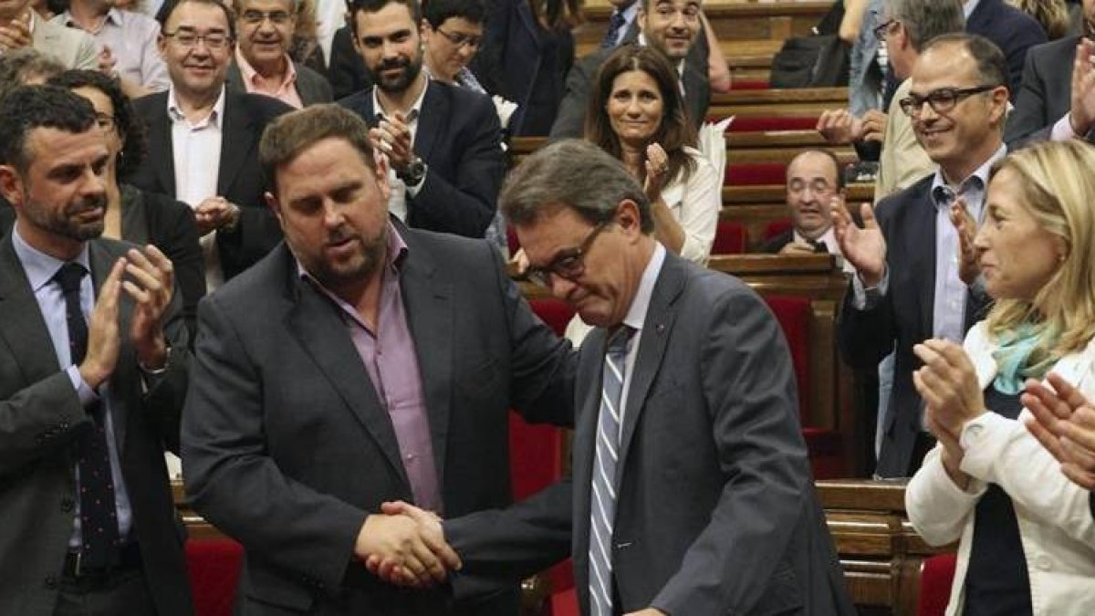 El presidente de la Generalitat, Artur Mas, estrecha la mano del lider de ERC, Oriol Junqueras, ante el aplauso de sus compañeros de partidos, tras la aprobación, hoy en el pleno del Parlamento de Cataluña, de una resolución pactada por los cuatro partido-Foto: EFE / TONI GARRIGA
