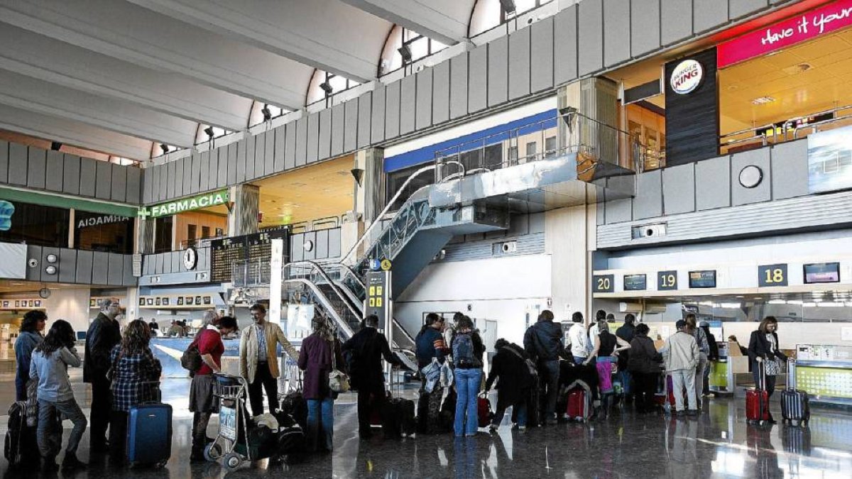 Varios viajeros esperan cola para facturar sus equipajes en el aeropuerto de Barajas-El Mundo