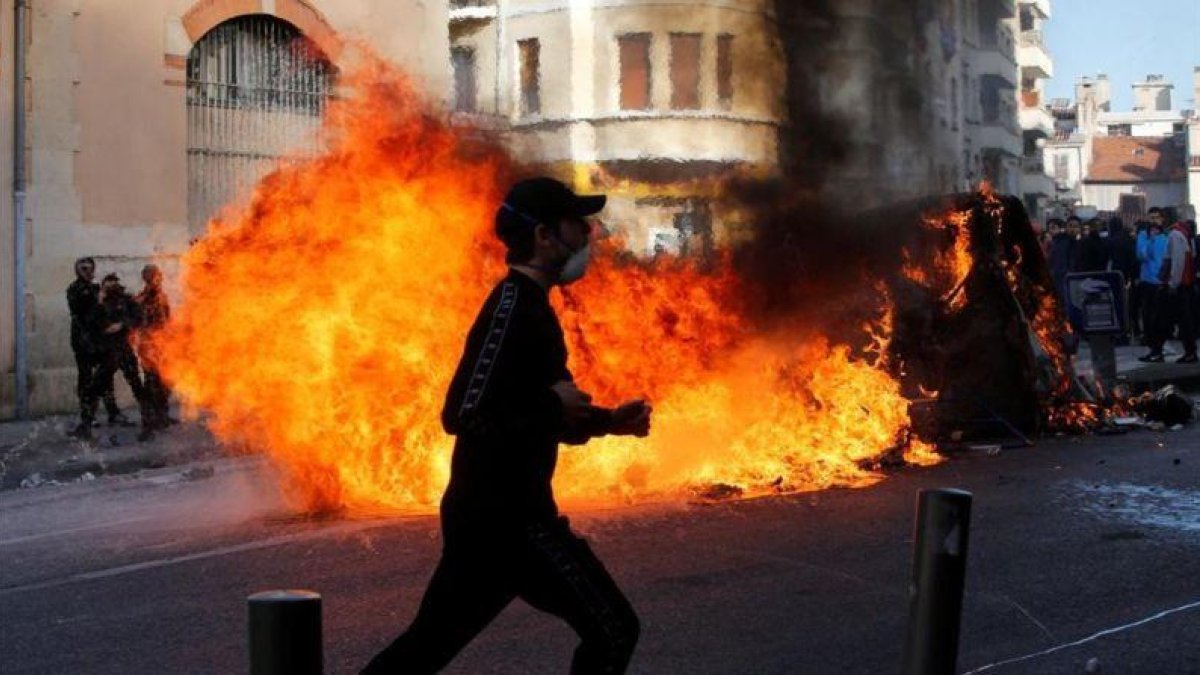 Unos jóvenes queman contenedores de basura en Marsella durante una manifestación contra los planes fiscales del Gobierno francés.-JEAN-PAUL PELISSIER (REUTERS)