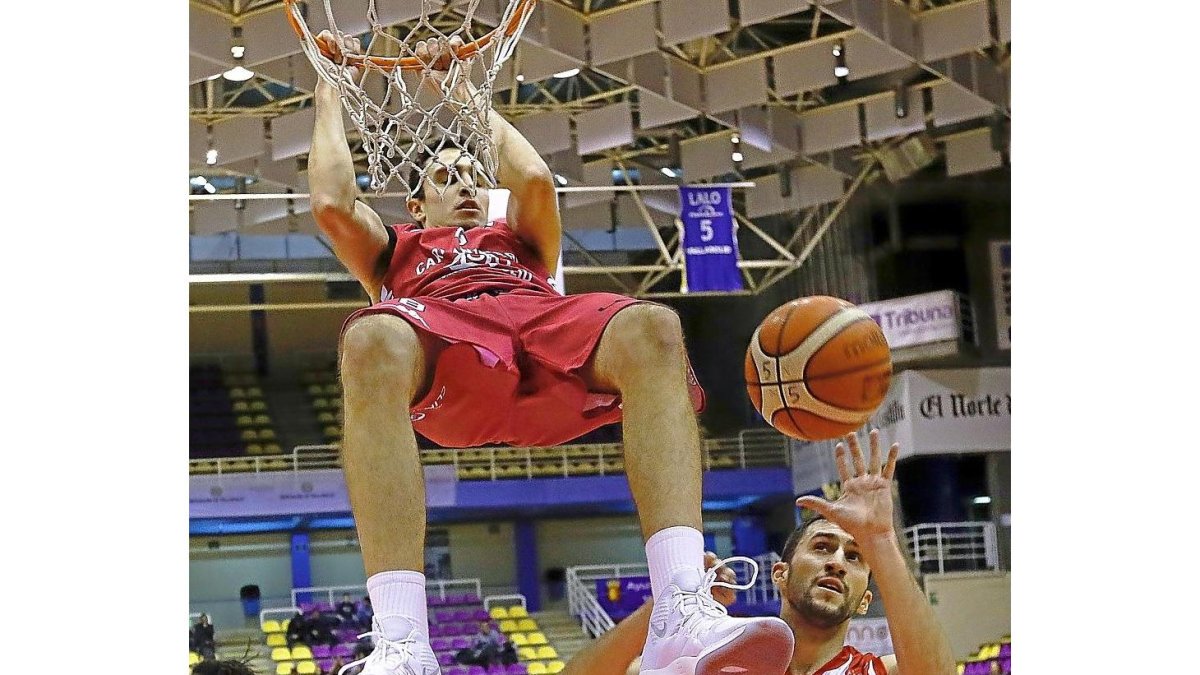 Álex Reyes machaca el aro del Covirán Granada ante la mirada de Manuel Rodríguez.-J.M. LOSTAU