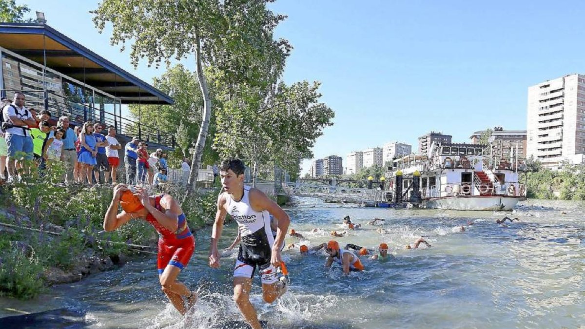 Los participantes de la competición salen del río Pisuerga para comenzar la prueba de bicicleta.-Ical
