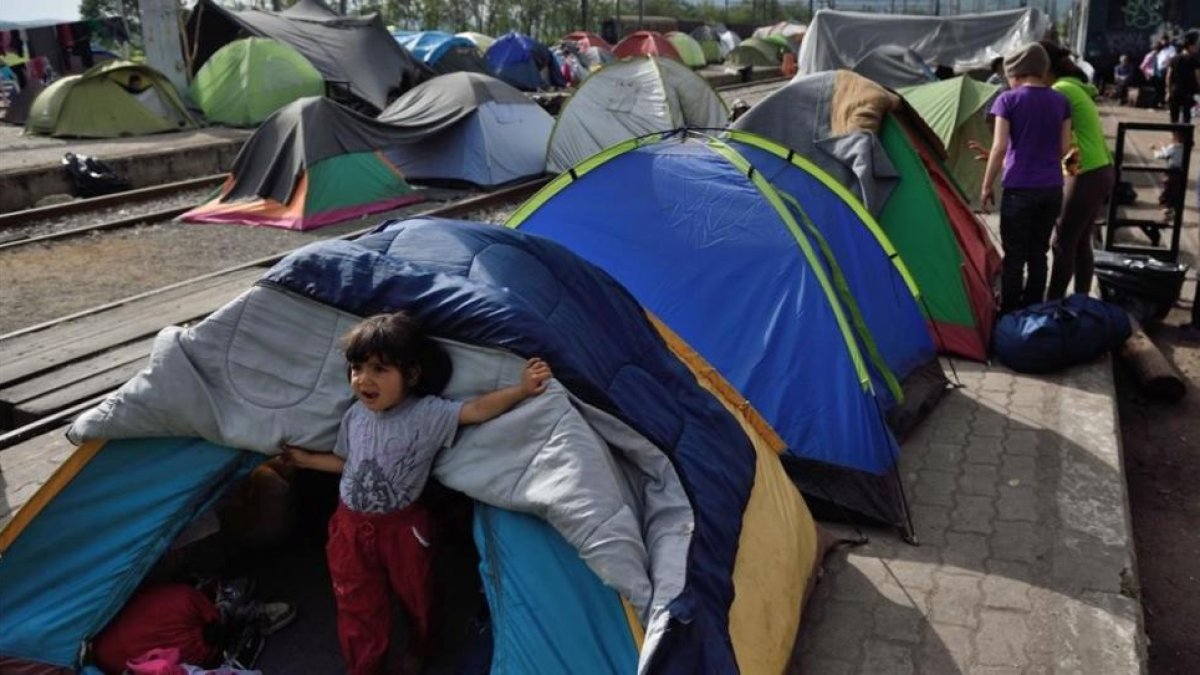 Un niño sale de una tienda en el improvisado campamento de la frontera griega con Macedonia cerca de Idomeni.-DANIEL MIHAILESCU