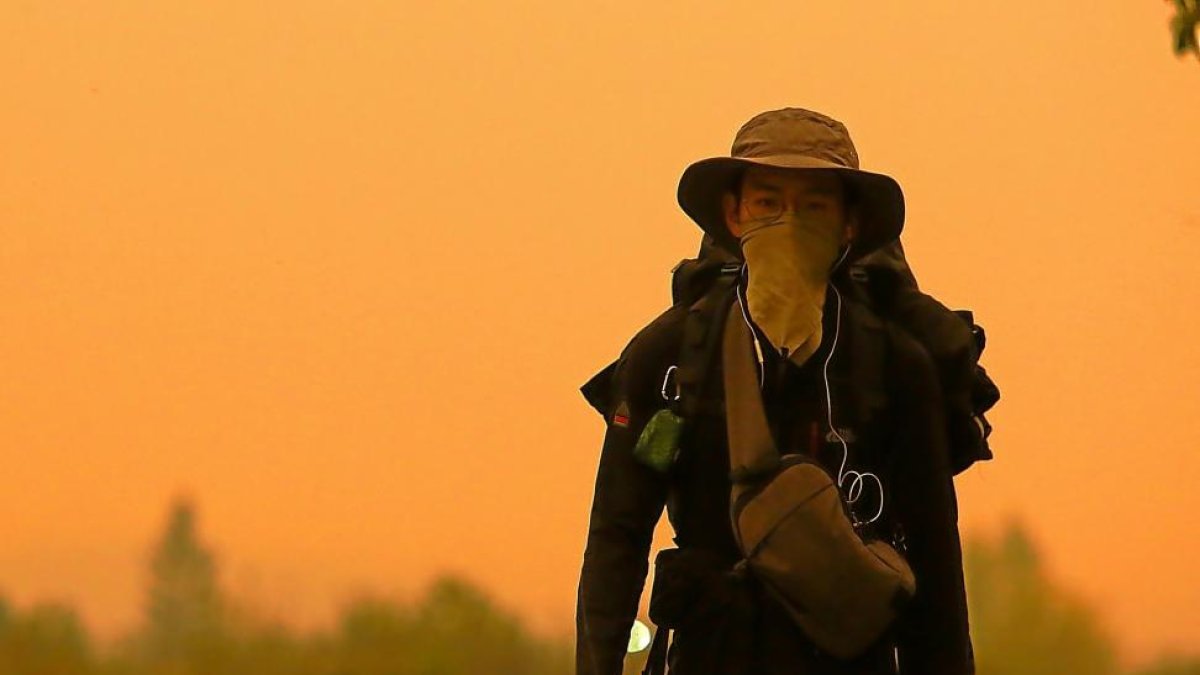 Un peregrino se protege del humo y las cenizas, a su paso por la en la comarca del Bierzo.-ICAL