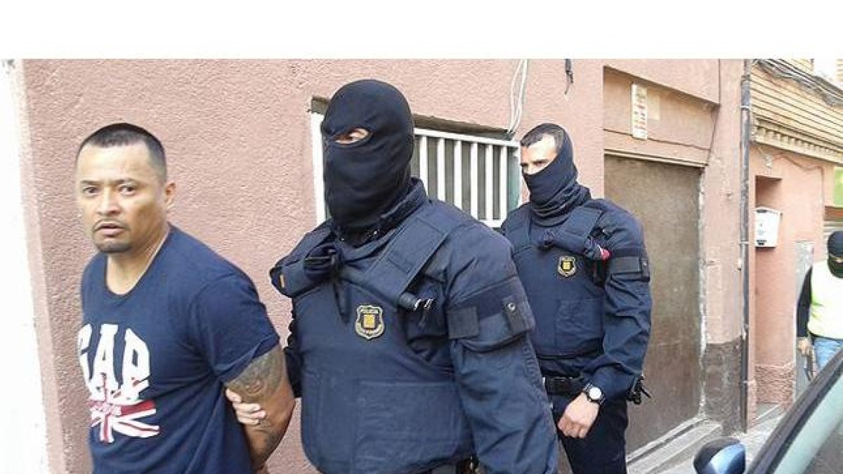 Imagen cedida por la Cadena Ser, en la que dos mossos se llevan detenido, en Santa Coloma de Gramenet, a uno de los presuntos miembros de la banda de Latin Kings desarticulada este miércoles.-Foto: CADENA SER