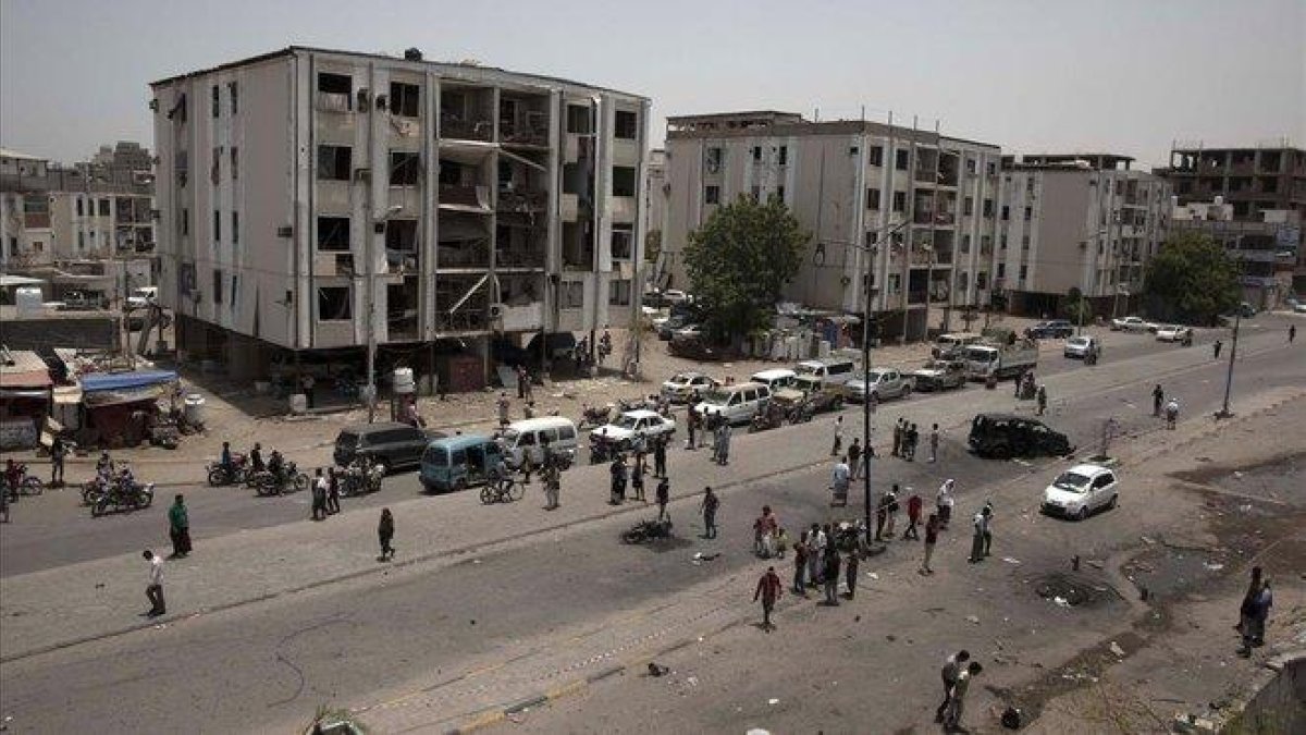 Civiles y fuerzas de seguridad permanecen a las afueras de la comisaría de policía atacada, este jueves, en el centro de Adén.-NARIMAN EL-MOFTY (AP)