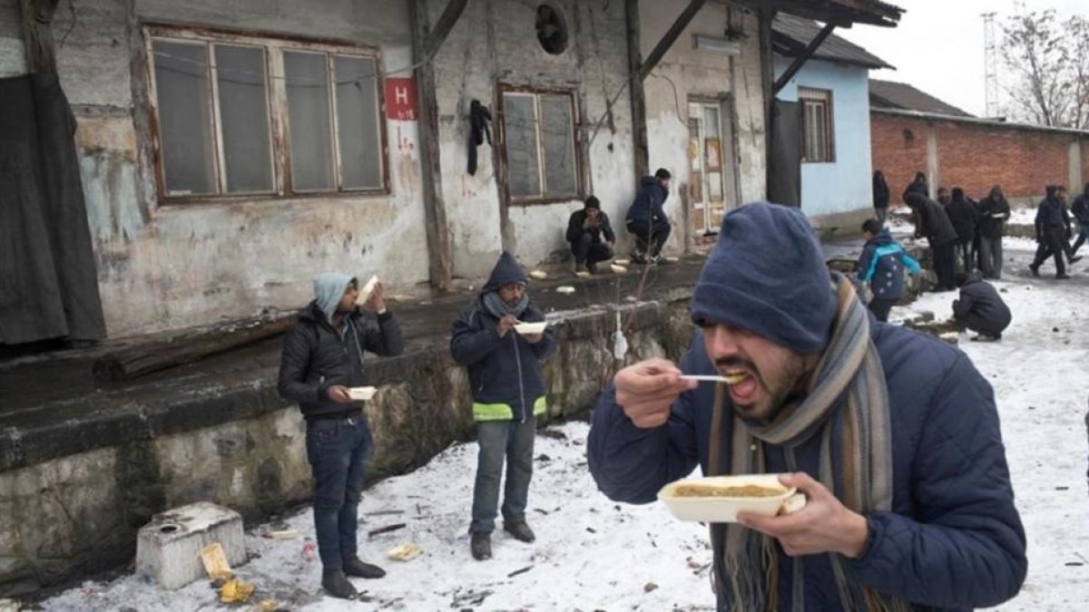 Refugiados comen en el exterior de un almacén abandonado en Belgrado.-MSF / MARKO DROBNJAKOVIC