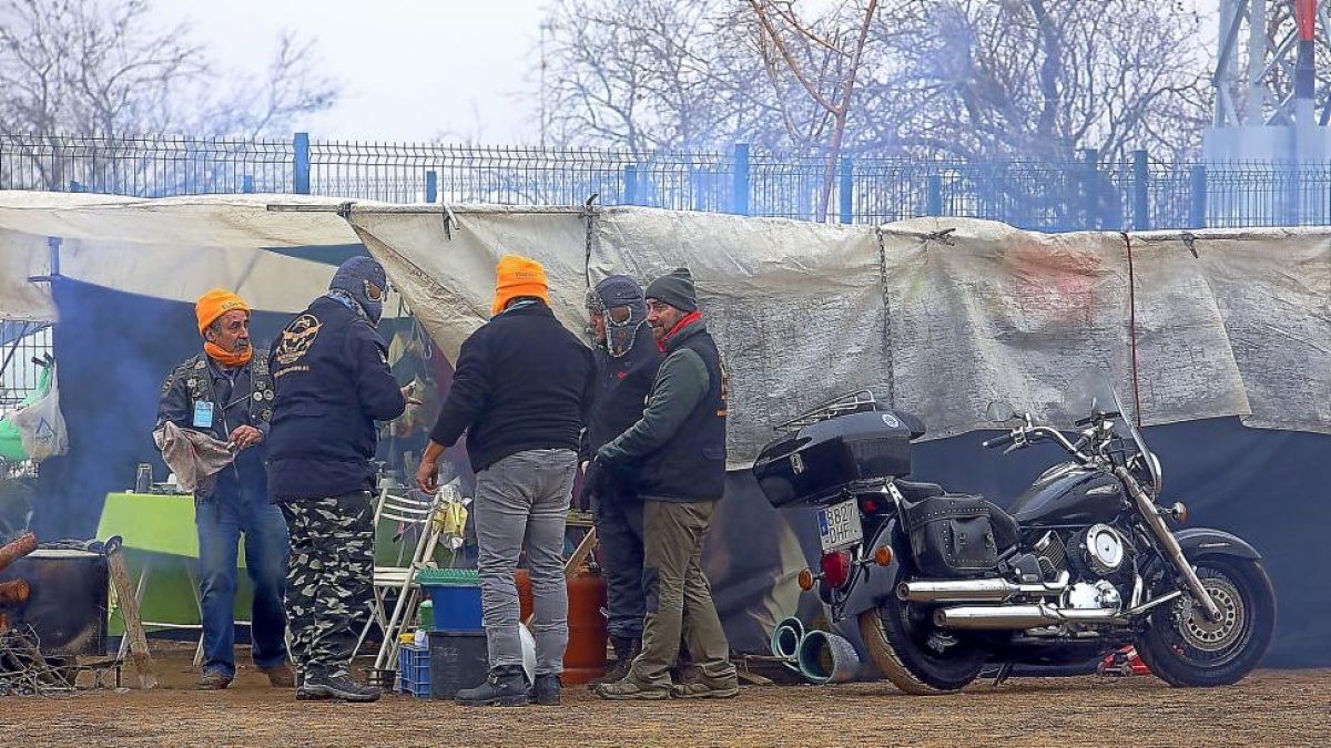 Varios moteros se preparan para comer en la zona de acampada, junto a sus tiendas.-ICAL