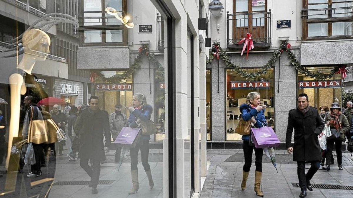 Dos personas pasean con bolsas de compras por la calle Santiago.-MIGUEL ÁNGEL SANTOS