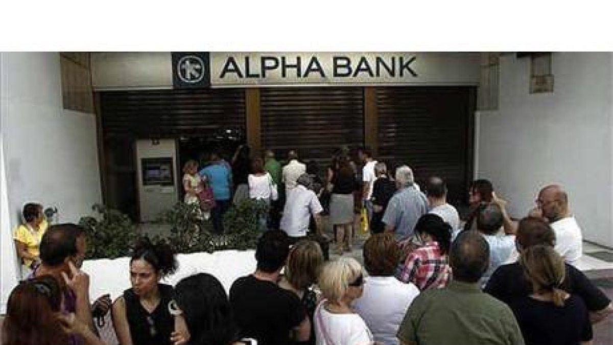 Decenas de personas hacen cola para sacar dinero de un banco en Atenas.-ALEXANDROS VLACHOS / EFE