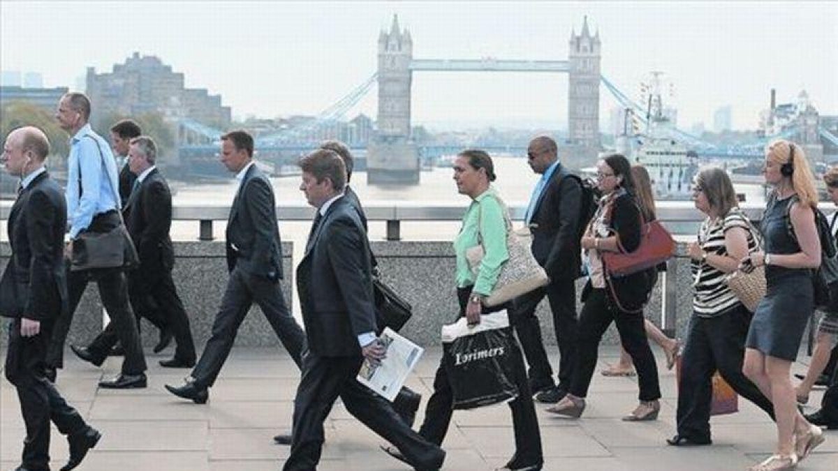 Empleados de la City londinense atraviesan el puente de Londres para dirigirse al trabajo, el pasado agosto.-REUTERS / LUKE MCGREGOR