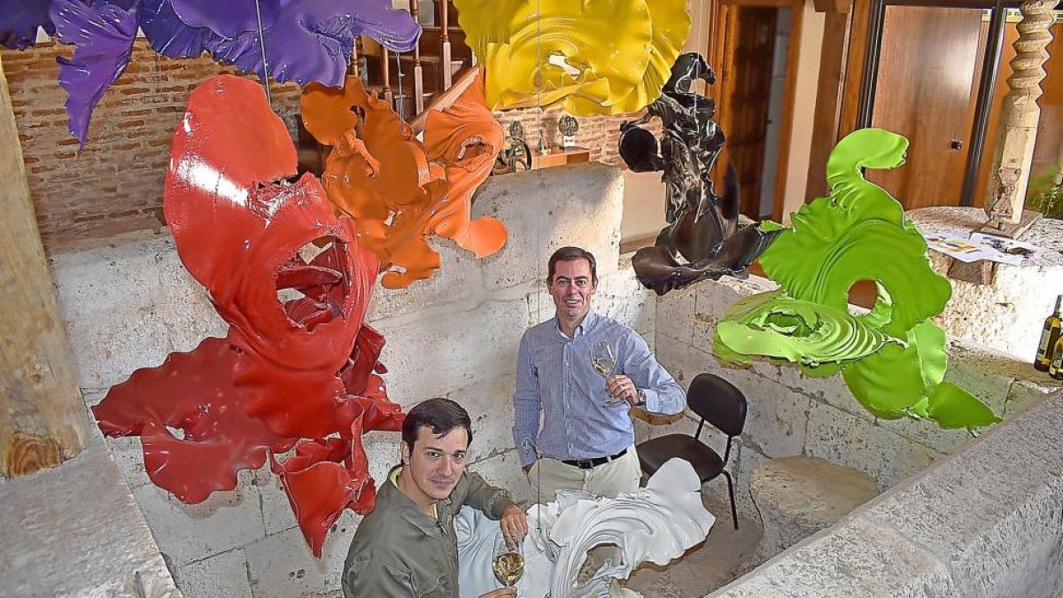 El enólogo Alberto Martínez (en primer término) y Pablo del Villar, en el interior del lagar de piedra, bajo la obra del artista Andrés Coello.-ARGICOMUNICACIÓN