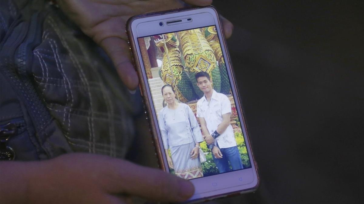 La tia de Ekapol Chanthawong muestra una foto en el móvil del entrenador en la que aparace junto a su abuela.-AP