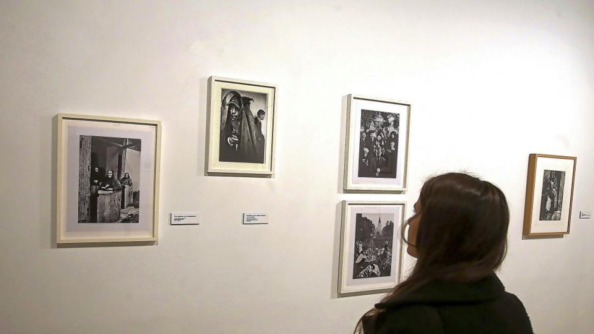 Una mujer contempla algunas de las fotografías de Luskacová.-ICAL