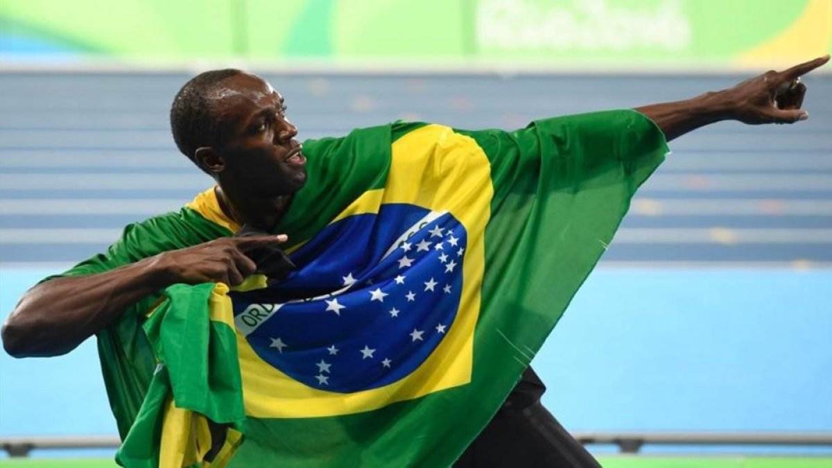 El Bolt camaleónico, envuelto en la bandera de Brasil.-AFP / ERIC FEFERBERG