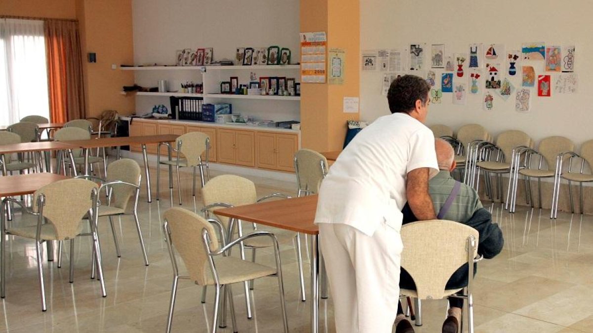 Un cuidador ayuda a una persona mayor en una residencia para la tercera edad. E. M.
