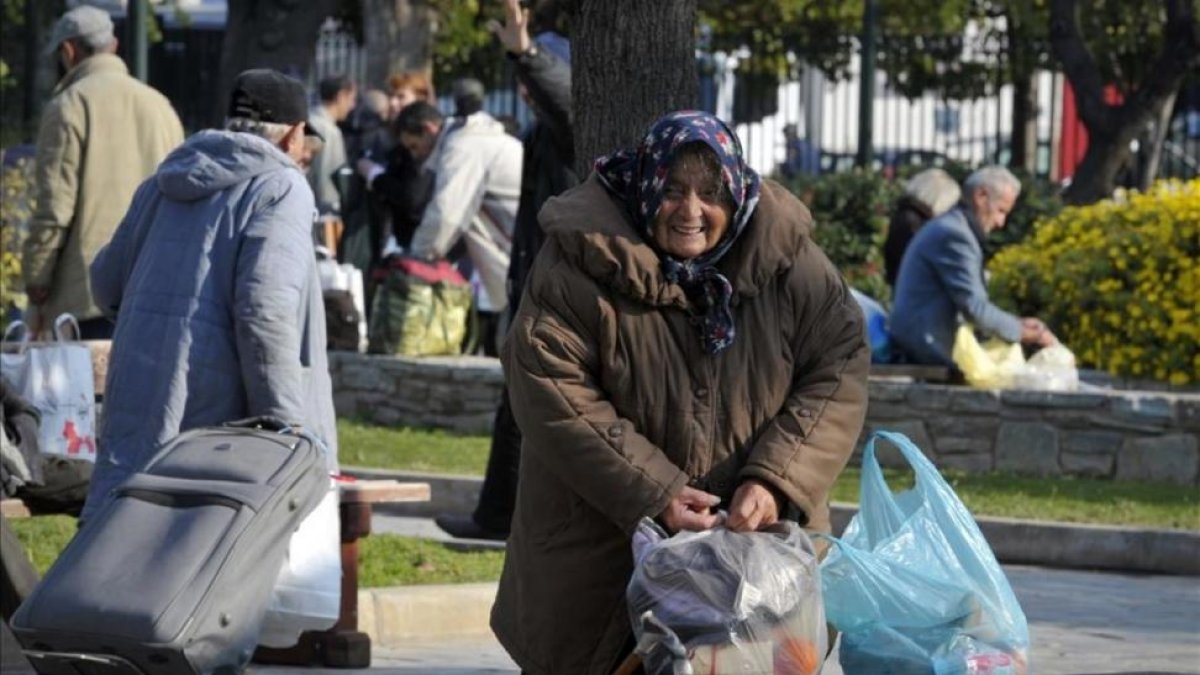 Una anciana sintecho recoge sus pertenencias en Atenas.-LOUISA GOULIAMAKI