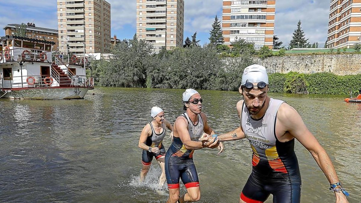 Un triatleta del Tetuán ayuda a salir del agua a su compañera de equipo.-J.M.LOSTAU
