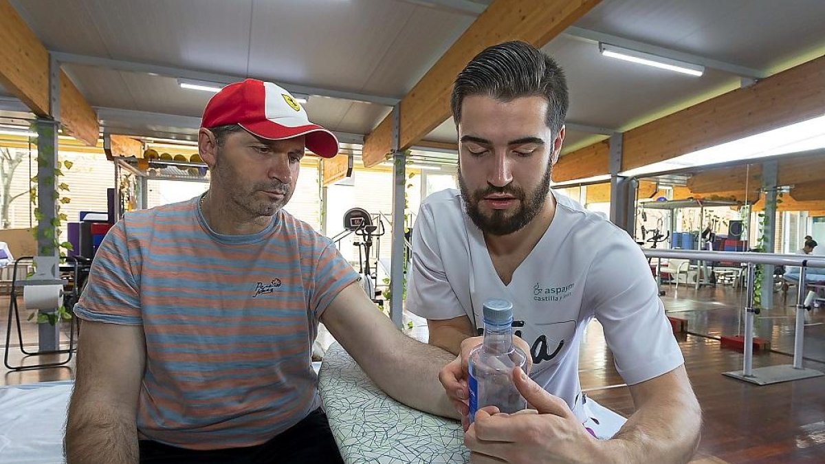 El fisioterapeuta Luis César trabaja el tono muscular de la mano izquierda de Gencho Ivanov para que logre agarrar una botella.-PABLO REQUEJO