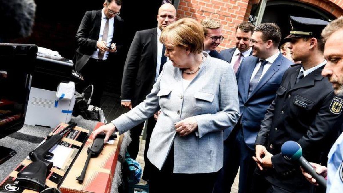 La cancillera alemana Angela Merkel observa armas de fuego durante su visita al Departamento Federal de la Policía en Pasewalk.-EFE / FILIP SINGER