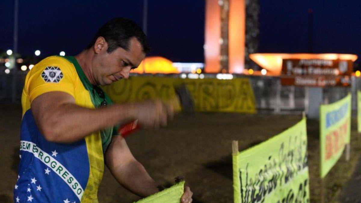 Un partidario de Rousseff clava un cartel en las afueras del senado brasileño.-ANDRESSA ANHOLETE / AP / AFP