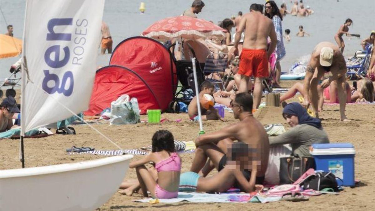 Una mujer en 'burkini', junto a su familia, en la playa de Roses.-JOAN CASTRO / ICONNA