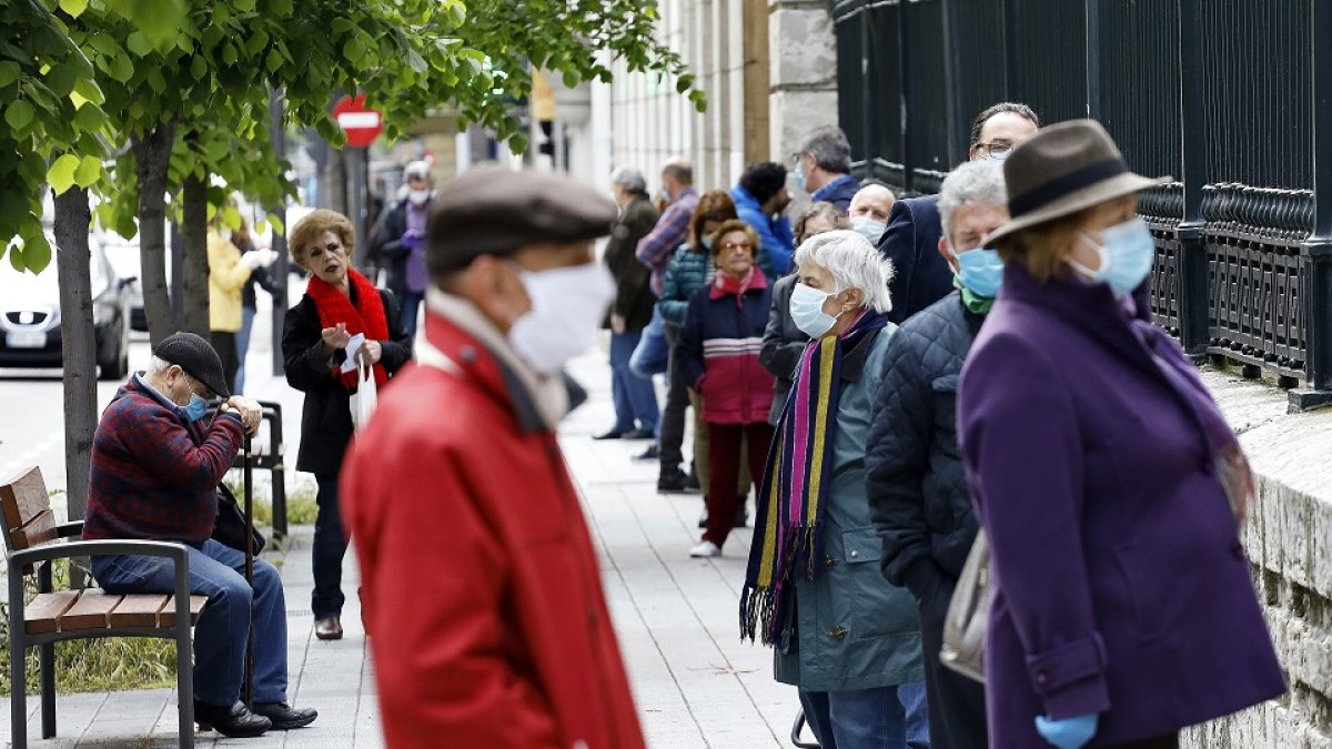 LARGAS COLAS PARA HACER TRÁMITES BANCARIOS EN VALLADOLID. La calle Duque de la Victoria de Valladolid dejó, a primera hora de ayer, imágenes de una multitud de personas haciendo cola para realizar trámites presenciales en la sucursal bancaria del BBVA. Un escenario similar al que se sigue viendo en varios supermercados.- J.M. LOSTAU