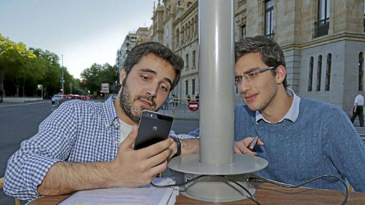 Dos jóvenes en el punto de carga móvil de la plaza de Zorrilla.-A. Mingueza