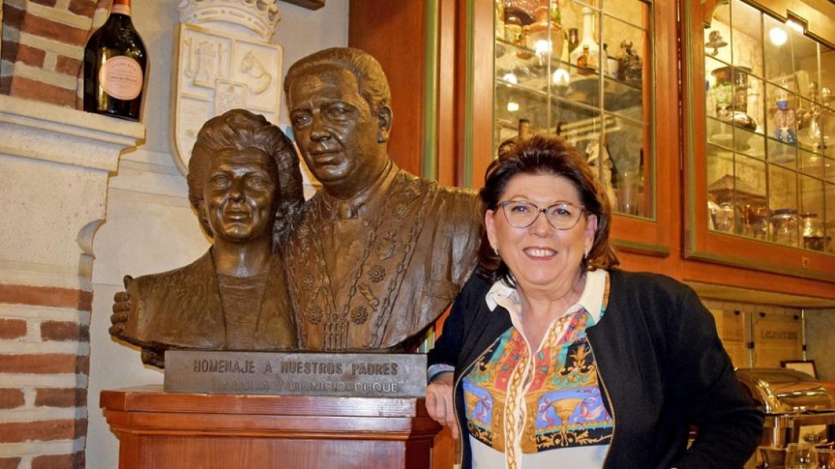Marisa Duque, junto al busto de bronce de sus padres, situado en el interior del mesón segoviano.-ARGICOMUNICACIÓN
