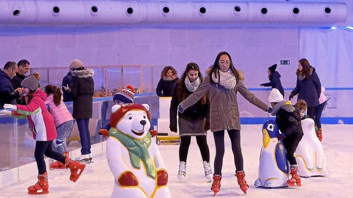 Varios niños y jóvenes patinan y juegan en la pista de hielo.-J.M. LOSTAU