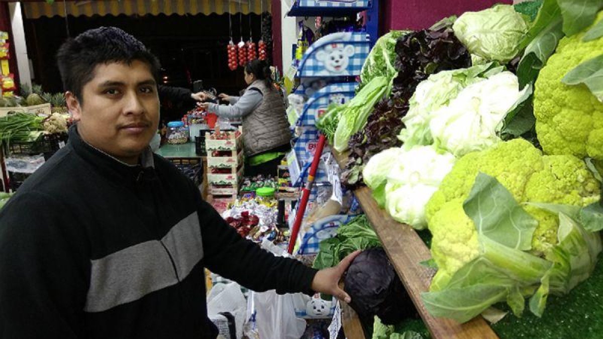 Éverson Fernández e Ibeth Kathia Suárez, al fondo, en su comercio de frutas y verduras de Barcelona.-EL PERIÓDICO