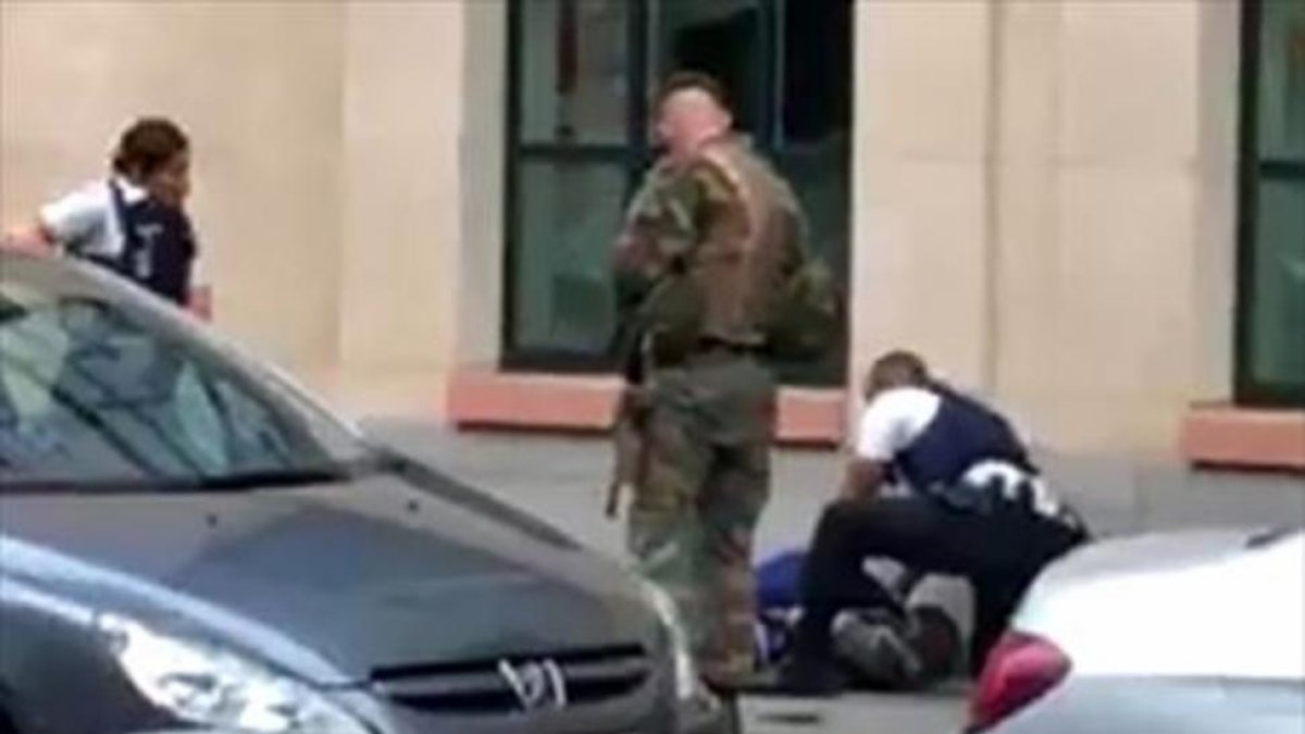 Dos policías y un militar, junto al hombre abatido ayer en Bruselas.-AFP