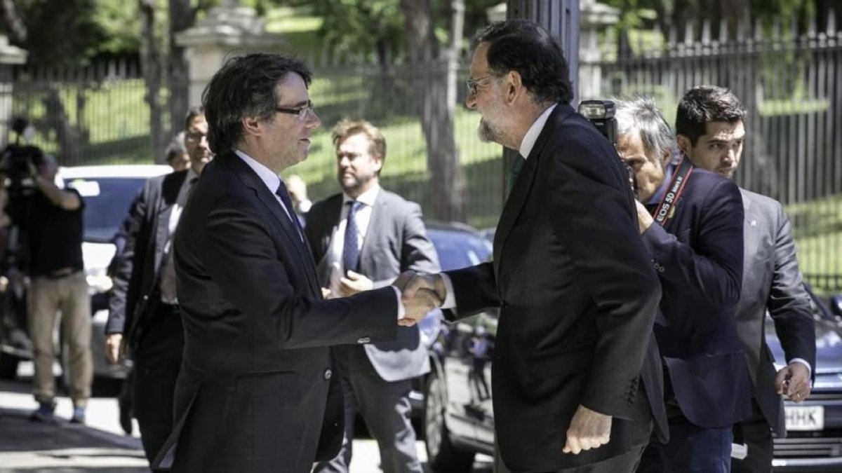 Carles Puigdemont y Mariano Rajoy se saludan este viernes, en Barcelona, antes de la inauguración del Salón de Automóvil de Barcelona.-JOAN CORTADELLAS