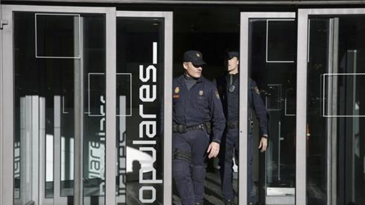 Dos policías salen de la sede central del PP, en la calle Génova de Madrid.-