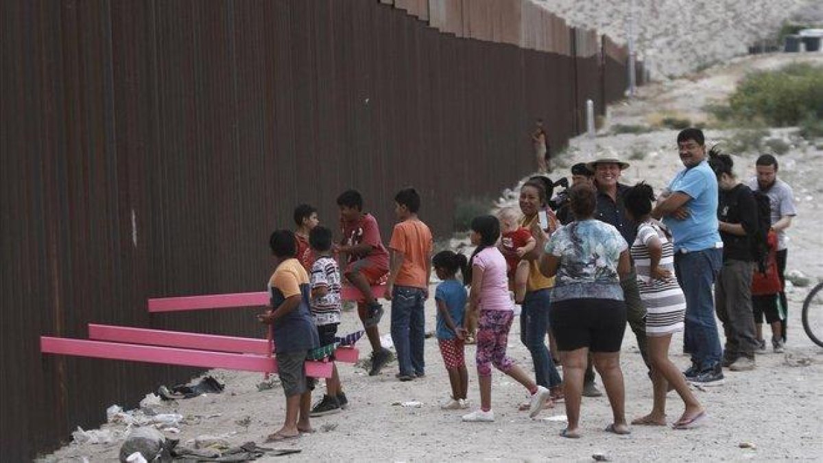 Niños juegan en un balancín situado en el muro de México a su paso por Ciudad Juarez.-AP
