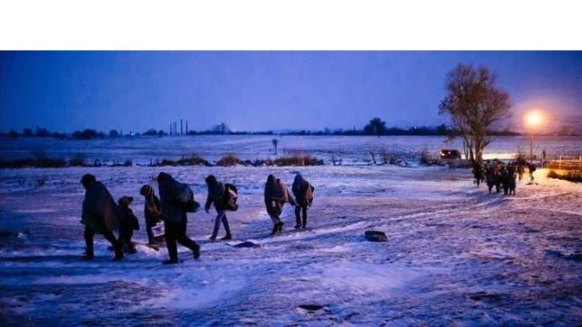 Migrantes y refugiados caminan por un campo cubierto de nieve tras cruzar la frontera de Macedonia con Serbia, cerca de la población de Miratovac, este domingo.-AFP / DIMITAR DILKOFF