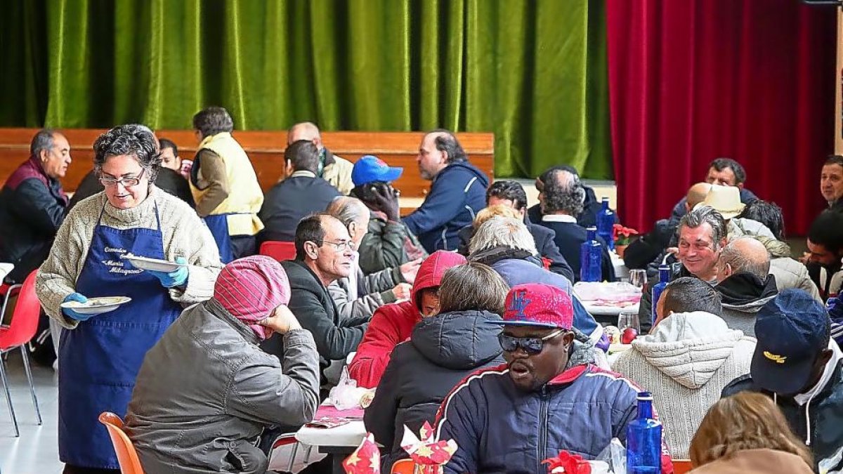 Una voluntaria sirve los platos durante la comida de Navidad en el comedor social de La Milagrosa.-PABLO REQUEJO