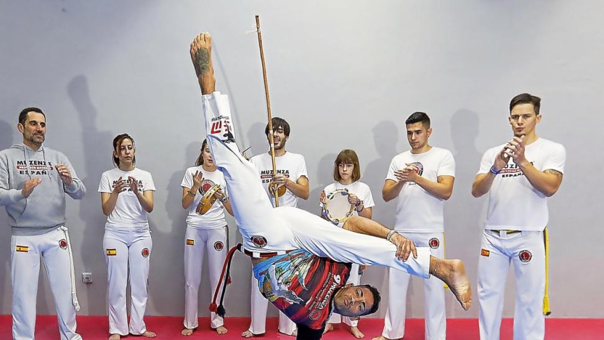 Flavio Oliveira realiza un acrobático movimiento ante la mirada de sus alumnos, que le acompañan con la música.-J. M. LOSTAU