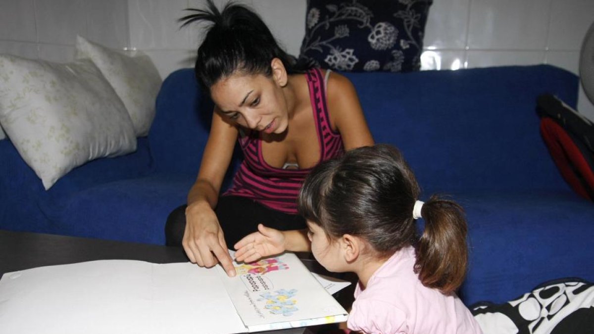 Una madre ayuda a su hija con los deberes encargados en el colegio.-J. MARTI