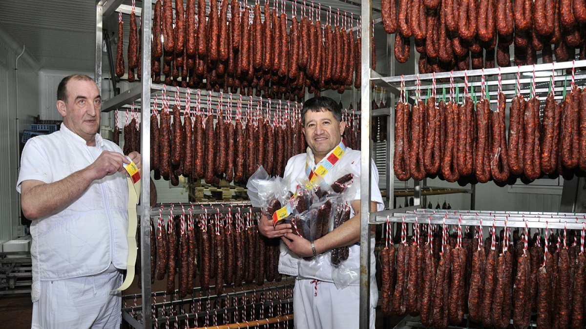 José Luis (izquierda) y Wilmar junto a unos carros de chorizos recién elaborados y listos para el secado. En unos años ha alcanzado a la morcilla como producto estrella en ventas y premios. / V. GUISANDE