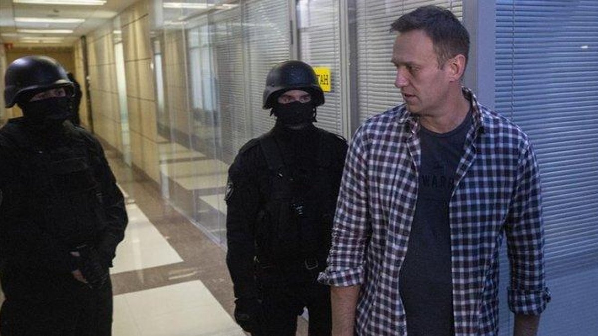 Alexei Navalni, en sus oficinas con dos policías, ayer.-EFE EPA SERGEI ILNITSKY